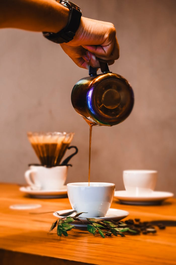 Barista pouring hot coffee into a cup, showcasing a cozy café atmosphere.
