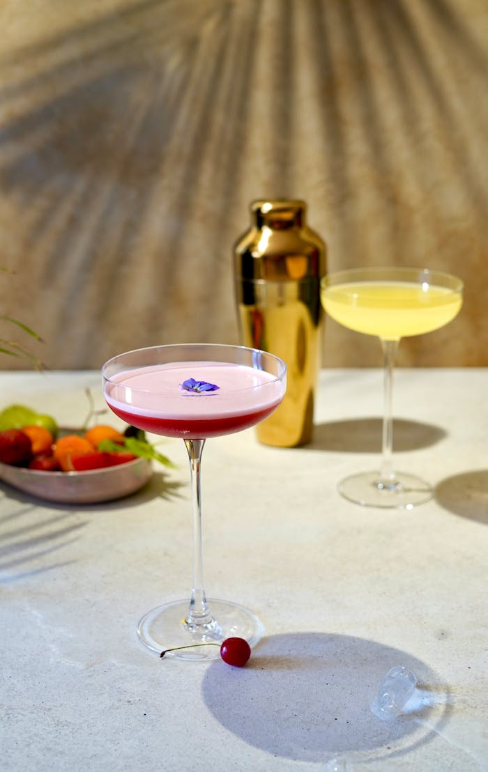 A stylish cocktail setting with a pink and yellow drink, perfect for a summer refreshment.