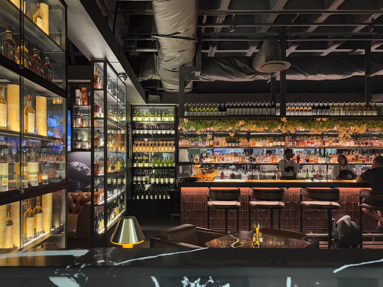 Luxurious modern bar with wide selection of spirits, cozy ambiance, and attentive bartenders.